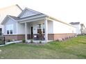 Inviting single-story home featuring a brick foundation, a welcoming front porch, and well-manicured lawn at 360 Lincoln W Cir, Fortville, IN 46040