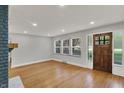 Bright living room featuring hardwood floors, a cozy fireplace, and a wooden front door at 4775 E 56Th St, Indianapolis, IN 46220