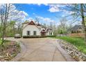 Elegant home featuring an expansive driveway, beautiful landscaping, and manicured lawn at 5212 Knollton Rd, Indianapolis, IN 46228