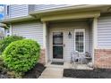 Charming front door entrance enhanced by a neat shrub, gray chair and miniature statue at 5453 Nighthawk Way, Indianapolis, IN 46254