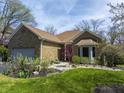 Charming stone home featuring an attached garage and beautifully landscaped front yard at 8069 Middle Bay Ln, Indianapolis, IN 46236