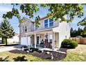 Side view of a two-story home showcasing a covered porch, landscaped garden, and classic architectural details at 12981 Coyote Run, Fishers, IN 46038