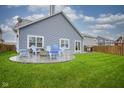Lush backyard featuring a stone fire pit with chairs, well-kept lawn, and a grill at 1299 W Crystal Dr, Fortville, IN 46040