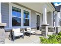 Inviting front porch with stone accents, offering a relaxing seating area and stylish black front door at 14349 Marsdale Pl, Carmel, IN 46074