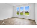 Bright living room featuring large windows with scenic backyard views and wood-look flooring at 2249 Aviary Ln, Danville, IN 46122