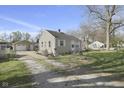 View of the home and detached garage with a long driveway and well-kept lawn at 413 Vasbinder Dr, Anderson, IN 46017