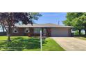 Lovely brick home featuring a well-manicured lawn and flower-adorned address post at 5444 S Holiday Dr, Columbus, IN 47203