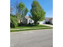 Well-maintained home featuring fresh green lawn and mature trees under a clear sky at 5912 Accent Dr, Indianapolis, IN 46221
