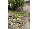Landscaped backyard with stone retaining wall, pond, and an array of blooming flowers adding beauty to the scenery at 7030 Central Ave, Indianapolis, IN 46220