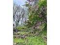 Multi-tiered landscaping with a stone retaining wall, a variety of plants, and trees offering serene outdoor living at 7030 Central Ave, Indianapolis, IN 46220