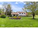 Charming two-story home with a large yard, mature trees, and manicured flower beds at 7440 Graham Rd, Indianapolis, IN 46250