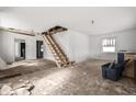 Open concept living room featuring unfinished staircase and ample natural light at 940 N Chester Ave, Indianapolis, IN 46201