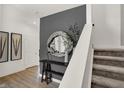 Bright hallway featuring hardwood floors, decorative mirror, and a staircase with carpeted steps at 11824 Vale St, Indianapolis, IN 46235