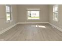 Bright living room features new flooring, fresh paint, and ample natural light streaming through large windows at 1615 N E St, Elwood, IN 46036
