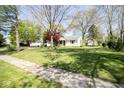 Traditional home set on a spacious lawn with mature trees and a paved sidewalk at 233 N Fenton Ave, Indianapolis, IN 46219