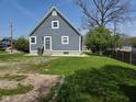 Exterior side view of home with blue siding, white trim, grass lawn, and concrete perimeter at 2819 W 16Th St, Indianapolis, IN 46222