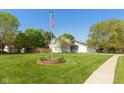 Expansive front yard with American flag and flower bed showcasing the home's curb appeal at 4651 Monterey Dr, Columbus, IN 47203