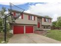 Home exterior with red garage doors, red shutters, and a basketball hoop in the driveway at 5335 Honey Comb Ln, Indianapolis, IN 46221
