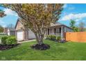 Beautiful home exterior with a blossoming tree, lush green lawn, and a charming front porch at 5622 Imperial Woods Cir, Indianapolis, IN 46224
