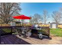 A wooden back deck features a grill, umbrella, table and chairs at 598 Collier St, Columbus, IN 47201