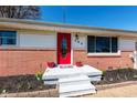 A bright red front door is the focal point of the front porch and surrounding flower beds at 598 Collier St, Columbus, IN 47201