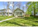 Inviting green home with a sunroom and a well-kept grassy yard at 6307 Broadway St, Indianapolis, IN 46220