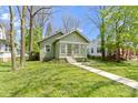 Quaint green home featuring a sunroom and a neatly manicured front yard at 6307 Broadway St, Indianapolis, IN 46220