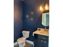 Stylish powder room featuring navy walls, modern fixtures, and a round mirror at 1115 Freshwater Ln, Cicero, IN 46034