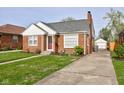Cozy home featuring a well-kept lawn, traditional brickwork, and a detached garage with a private driveway at 1209 N Downey Ave, Indianapolis, IN 46219