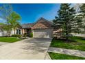 Brick home featuring a two-car garage, a well-kept lawn, and mature landscaping in a quiet neighborhood at 12210 Doncaster Ct, Fishers, IN 46037