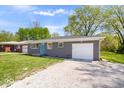 Charming one-story home featuring a gray brick exterior, a blue front door, and an attached garage at 1243 N Post Rd, Indianapolis, IN 46219