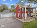 Exterior view showing home's red brick, white columns, and attached garage, blending style and convenience at 1394 N Michigan Rd, Shelbyville, IN 46176