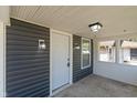A well lit covered porch features gray siding, concrete flooring, modern wall fixtures, and a white front door at 1627 Lawton Ave, Indianapolis, IN 46203
