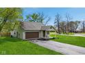 Charming single-story home with a brown garage door, light siding, green lawn and a paved driveway at 4525 Shelbyville Rd, Indianapolis, IN 46237