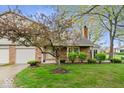 Charming two-story home with a well-maintained lawn, mature flowering tree, and attached garage at 7424 Prairie Lake Dr, Indianapolis, IN 46256