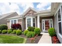 Beautiful home with brick facade, bay window, manicured bushes, and red flowers at 16204 Oakford Trl, Fishers, IN 46037