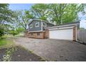View of the home's exterior showcasing the attached garage, brick accents, and driveway leading to the side entrance at 5719 Laurel Hall Dr, Indianapolis, IN 46226