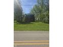 Two-story brick home featuring a small balcony, a large front lawn, and surrounded by trees at 6403 W Ralston Rd, Indianapolis, IN 46221