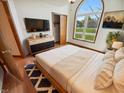 Bright bedroom with a large arched window, hardwood floors, and a modern dresser at 6618 Crystal Springs Dr, Avon, IN 46123
