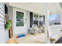 Cozy covered front porch with white railings, wicker furniture, and a decorative welcome mat next to the front door at 709 S Meridian St, Lebanon, IN 46052