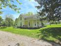 View of a yellow two-story home with a wraparound porch and red porch swing at 7561 N Hall School Rd, Monrovia, IN 46157