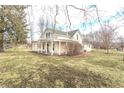 A view of a two-story home with a covered porch, lawn, and mature trees at 7561 N Hall School Rd, Monrovia, IN 46157