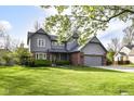 Beautiful gray two-story home with a manicured lawn, brick details, mature trees, and an attached two car garage at 8242 Windhaven Cir, Indianapolis, IN 46236