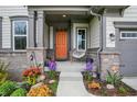 Inviting front porch with an orange door, featuring potted flowers and seating that adds a welcoming touch to the home at 10294 Pigato Dr, Zionsville, IN 46077