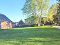 View of a brick single-story house with a lush lawn and mature trees in a quiet neighborhood at 1605 Fox Dr, Martinsville, IN 46151