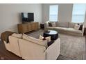 An open living room with a large neutral sofa, a dark wood coffee table, and a woven media console at 17364 Graley Pl, Westfield, IN 46074