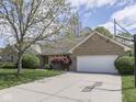 Brick house features a basketball hoop, two car garage, and mature tree in the front yard at 4759 Silver Hill Dr, Greenwood, IN 46142