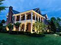 Elegant brick home with a two-story porch, showcasing well-maintained landscaping and evening lighting at 6655 Westminster Dr, Zionsville, IN 46077