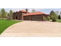 Exterior view of brick home with a red roof and two-car garage and extended circular driveway at 7901 Oaklandon Rd, Indianapolis, IN 46236