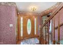 Traditional foyer with wood door, staircase, hardwood floors, and decorative wallpaper at 7901 Oaklandon Rd, Indianapolis, IN 46236
